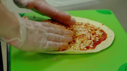 Hands Preparing a Meat and Cheese Tortilla Wrap