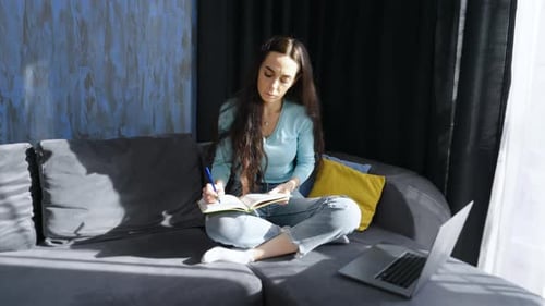 Woman Writes in Notebook and Uses Laptop