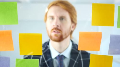 Geschäftsmann arbeitet im Büro an Haftnotizen auf Glas