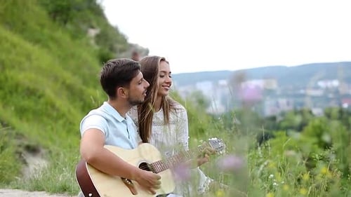 Romantischer Mann spielt Gitarre für Frau in der Natur