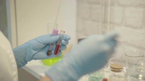 Gloved Hand Holds Test Tubes in Laboratory Setting