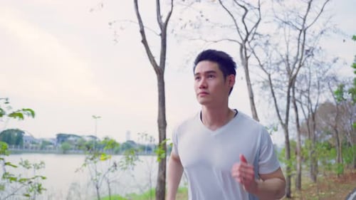 Asian young handsome active sport man running jogging workout on street in public park