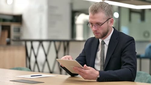Serious Professional Businessman Using Tablet in Office