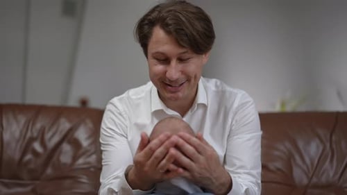 Front View Portrait of Happy Caucasian Father Talking to Infant Son Smiling Sitting on Comfortable