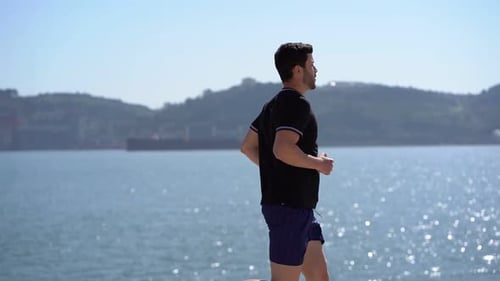 Athletic Man Jogging by the Ocean on Sunny Day