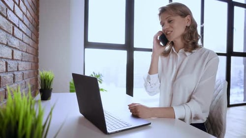Happy Woman Talking on Phone at Desk
