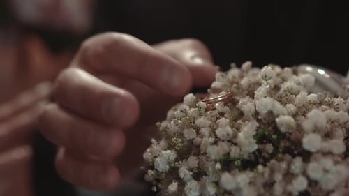 Der Bräutigam nimmt einen Verlobungsring, der während einer Hochzeitszeremonie in der Zeitlupe in Blumen liegt