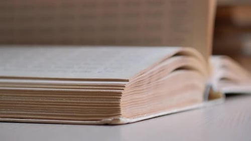 Buch. Weibliche Hände blättern über die Seiten eines alten Buches in der Bibliothek. Konzept des Lesens und der Bildung