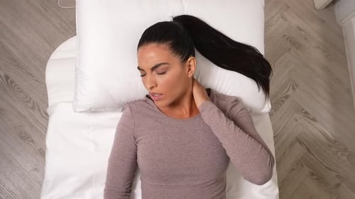 Woman on Bed Touching her Neck