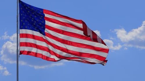 American Flag Waving Against Blue Sky Background