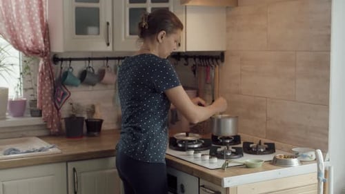 Woman Cooking Food on Gas Stove in Kitchen