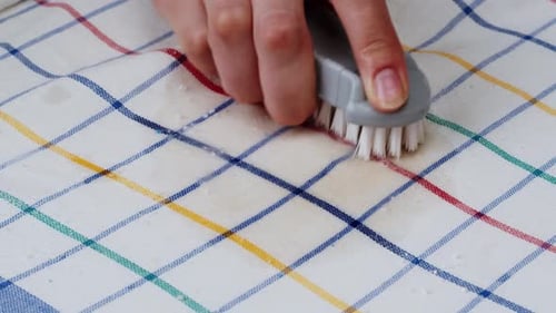 Hand scrubbing stain on colorful checkered cloth