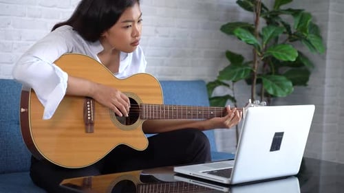 Young Woman Playing Acoustic Guitar at Home
