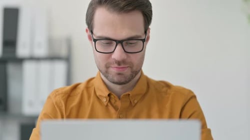 Close Up of Young Man Working on Laptop in Office
