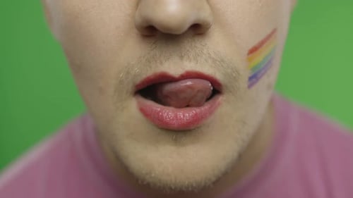 Hombre barbudo con labios pintados los lame sexualmente. Comunidad LGBT. transexual