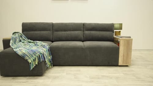 Stilvolles schwarzes Ecksofa mit einer hölzernen Seitenwand und einem gemütlichen Plaid