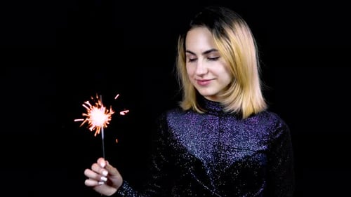 Woman Holding Sparkler in Front of Black Background