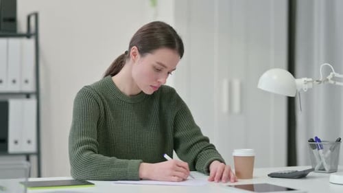 Young Woman Writing at Desk in Office
