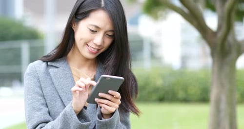 Smiling Woman Using Smartphone in Urban Park