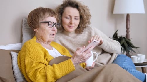 Woman Helping Senior Woman Use a Phone