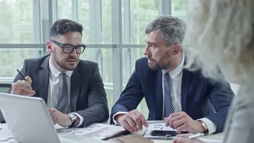 Men Discuss Business at Office Table with Laptop