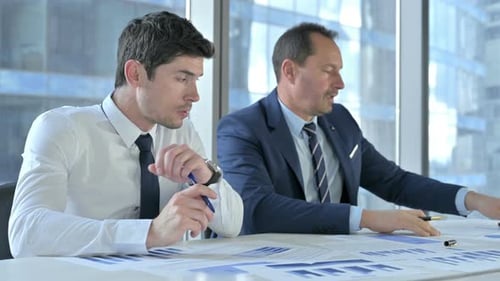 Businessmen Reviewing Financial Documents in Modern Office