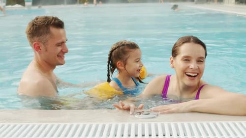 Fröhliche Familie, die Spaß im Pool hat