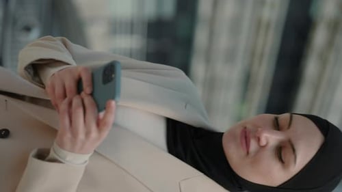 Woman with Head Covering Looking at Cellphone