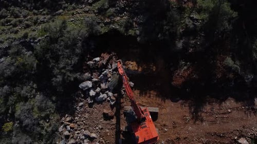 Orange Excavator Moving Rocks on a Hillside