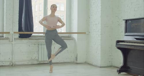 Ballet Dancer Practicing at Barre in Studio