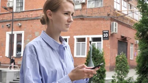 Blonde Woman Uses Phone on City Street