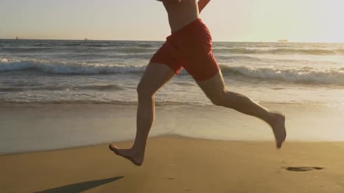 Male lifeguard running along the beach