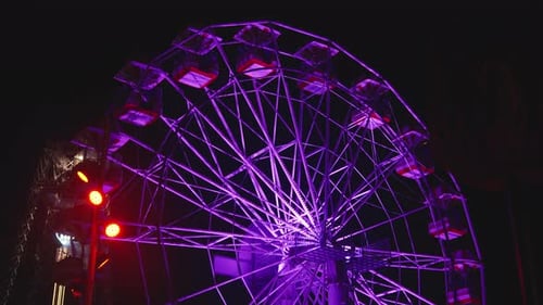 Illuminated Ferris Wheel Rotating in an Amusement Park At Night