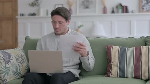 Man Working with Laptop and Documents at Home