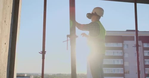 Engineer the Builder on the Roof of the Building Stands in VR Glasses and Moves His Hands Using the