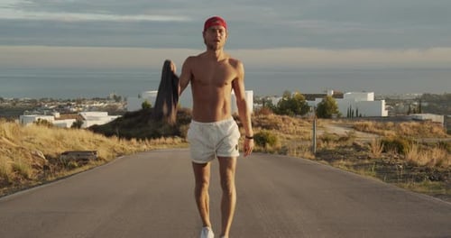 Man Walking Along Empty Road In Shorts