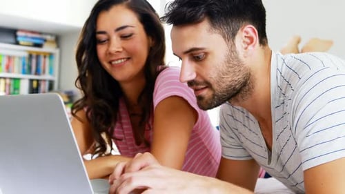 Couple Relaxing in Bed Using Laptop Together