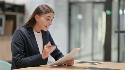 Woman Reviewing Paperwork in Office is Pleasantly Surprised