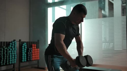 Caucasian Bodybuilder Hardly Working Out with Heavy Dumbbells in Gym