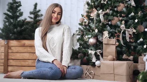 Woman Smiling by Christmas Tree with Presents