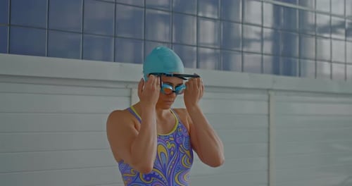 Woman Puts on Goggles at Indoor Pool