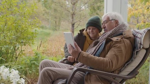 Boy and Senior Man Using Tablet on Terrace