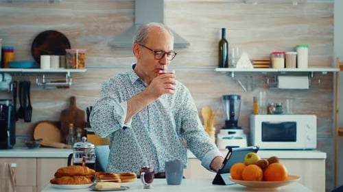 Senior Man Using Tablet in Sunny Kitchen