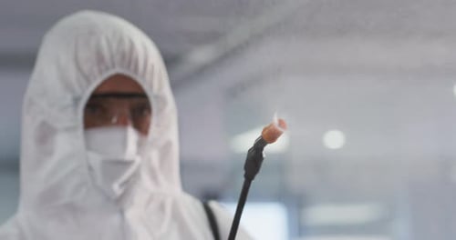 Health worker wearing protective clothes cleaning the office using disinfectant