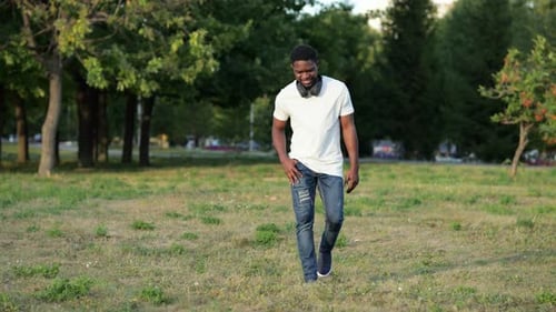 African American Man Walks in Green City Park on Lawn