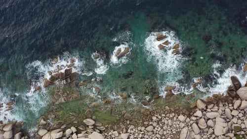 Les vagues de la mer roulent sur la côte rocheuse avec éclaboussures et mousse