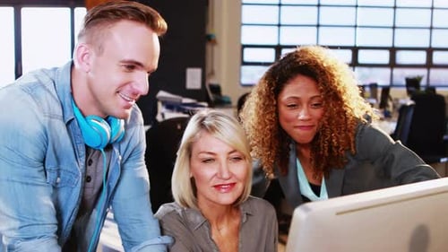 Femme d'affaires interagissant avec ses collègues tout en travaillant sur ordinateur