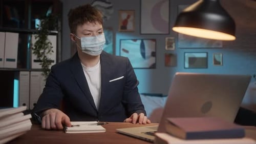 Young Adult Working at Desk with Laptop and Notepad