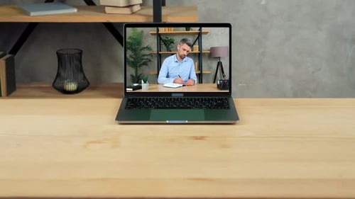 Laptop Displaying Man Writing Notes on Desk