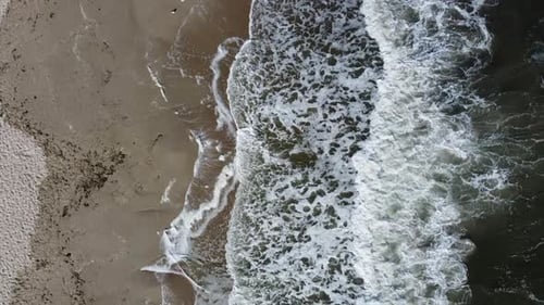 Drohnenflug über schöne Meereswellen am Sandstrand mit weißem Schaum